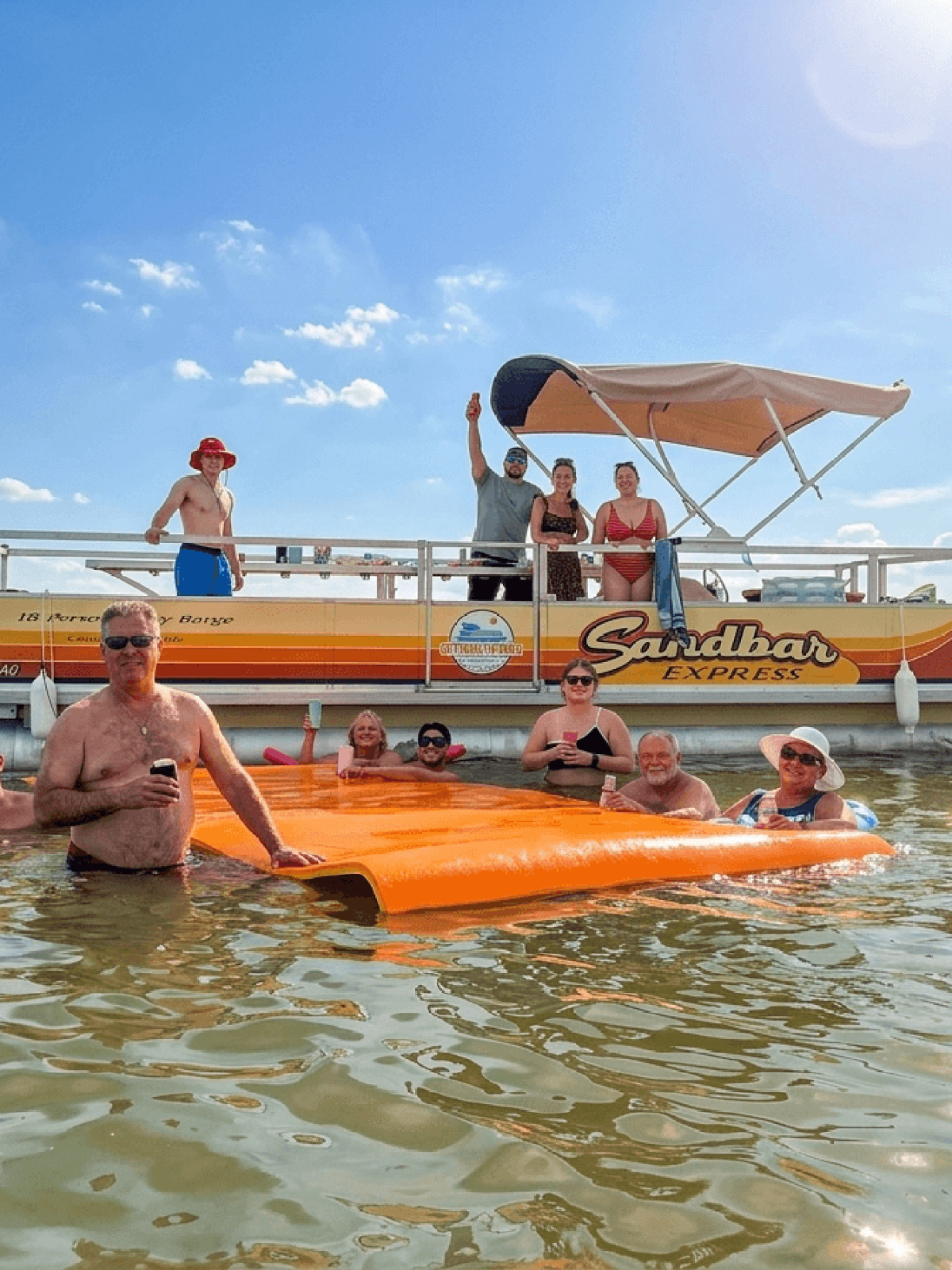Group of people in water near a pontoon boat with a canopy.
